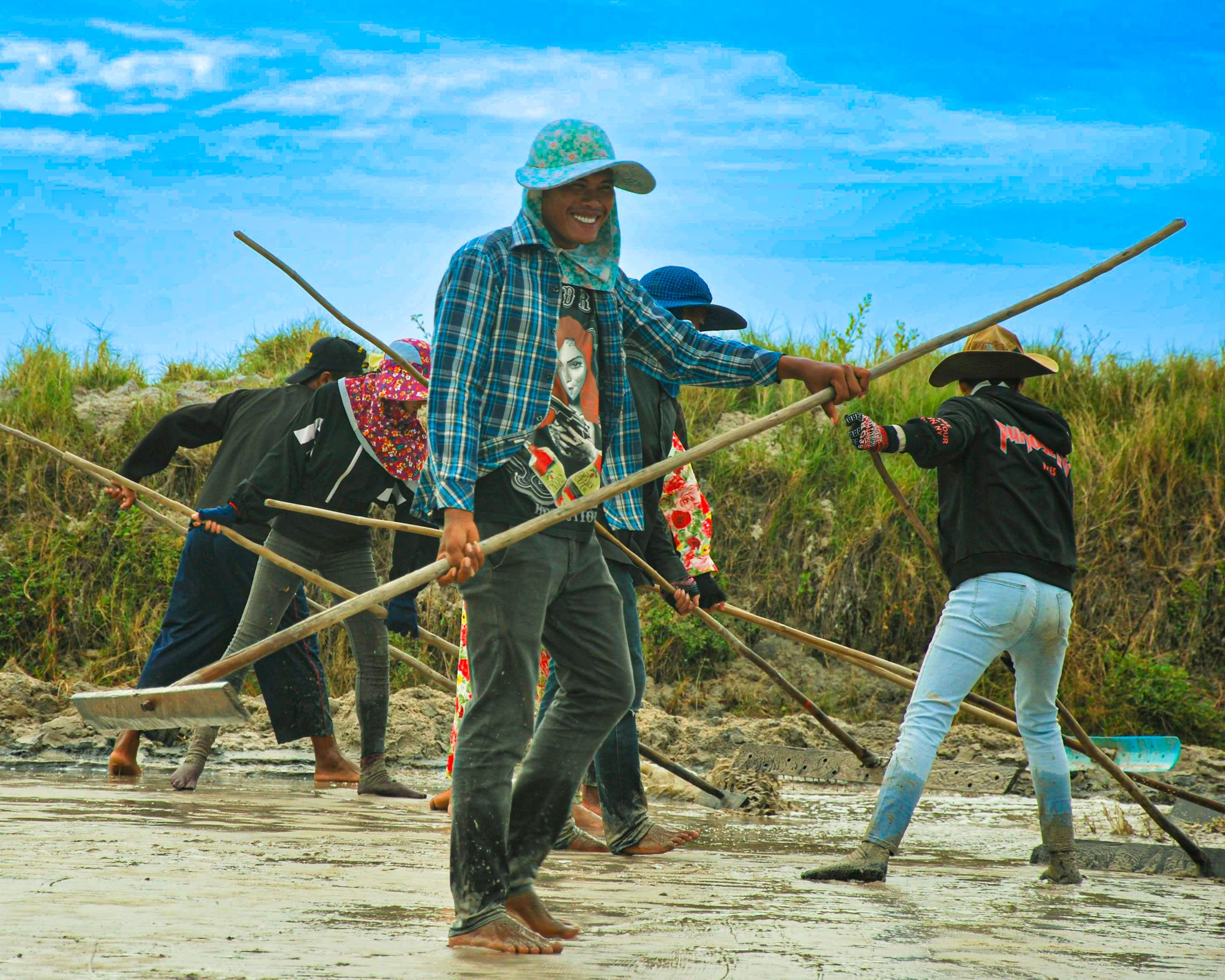 Salt workers with rakes sharing a laugh in the fields